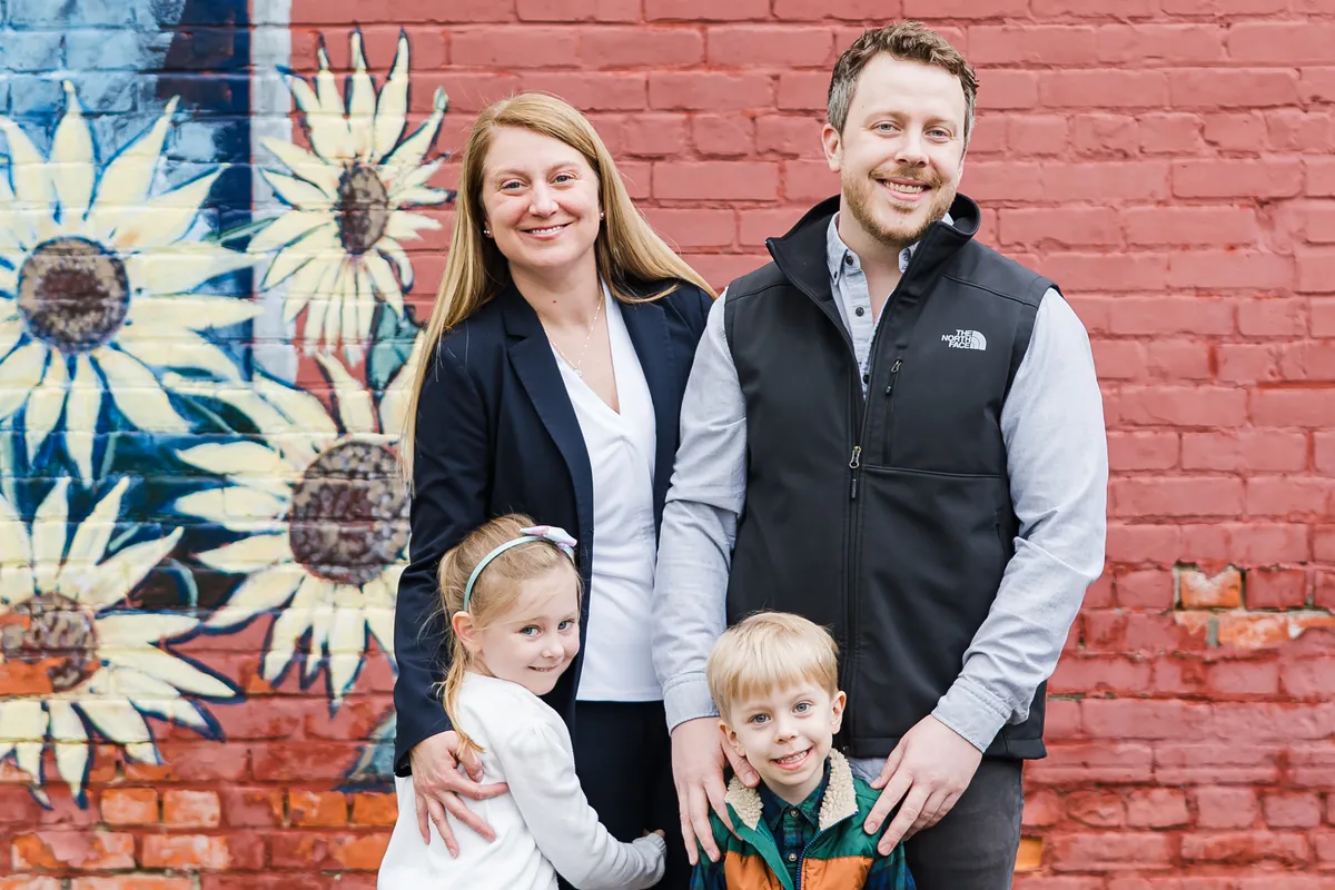 Alissa Brennan with her husband and two children in front of a sunflower mural in Rochester